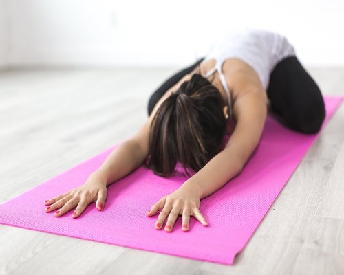 Woman doing light stretching or yoga on a mat at home