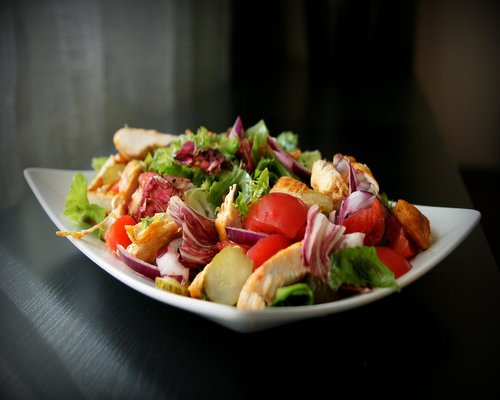 A person preparing a healthy homemade salad in a modern kitchen