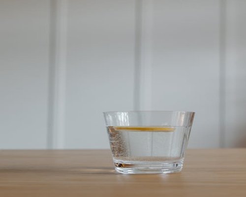 Glass of water with lemon on a wooden table