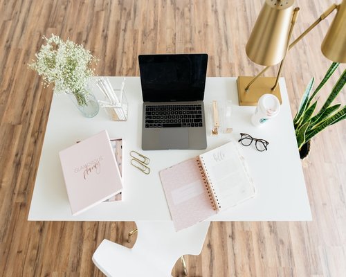 A well organized office desk with a laptop and a notebook